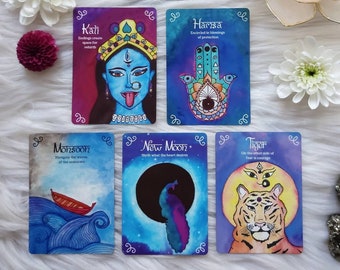 Könnte beinhalten: Draufsicht auf Tarotkarten mit Aquarellillustrationen und Text. Die Karten zeigen Bilder eines Halbmonds, einer blauhäutigen Gottheit, einer Hand, eines Tigers, eines Pfaus und eines Bootes auf Wellen. Eine brennende Kerze befindet sich in einem Lotusblütenhalter.
