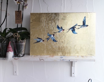 May include: A gold canvas painting with a flock of blue and white birds flying in formation. The painting is on a white shelf with a potted orchid and two gnomes.