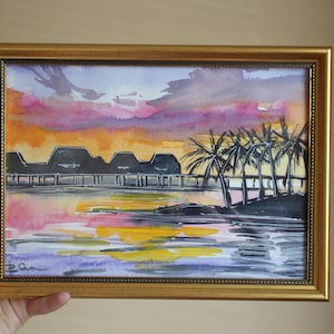 Puede incluir: Pintura acuarela de una puesta de sol sobre una isla tropical con palmeras y una fila de edificios en el fondo. El cielo es una mezcla de rosa, naranja y morado, y el agua es de un azul profundo.