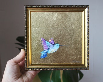 May include: A framed painting of a blue and purple hummingbird with gold leaf background.