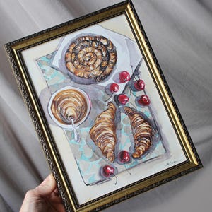 May include: Watercolor painting of a breakfast scene with a croissant, a pastry, a cup of coffee, and cherries on a blue and white patterned tablecloth.