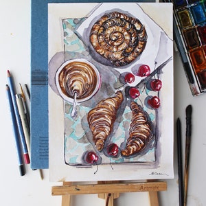 May include: Watercolor painting of a breakfast scene with a croissant, a pastry, a cup of coffee, and cherries on a tiled surface. The painting is on an easel with the word "Artimate" printed on the easel.