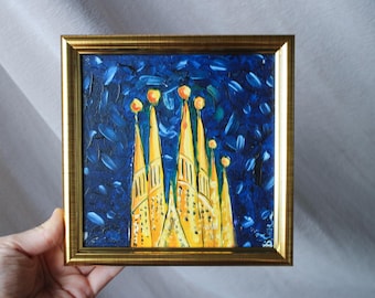 May include: A framed painting of a yellow building with multiple towers against a blue night sky. The building is painted in a stylized, almost cartoonish style, with thick brushstrokes and bright colors.