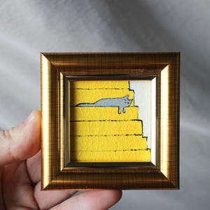 Mini tableau représentant un chat gris qui dort dans les escaliers, cadre 2 x 2 po. Tableau original fait main