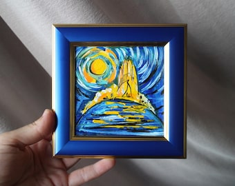 May include: A square painting in a glossy blue frame with a gold inner border. The artwork features a vibrant yellow sun set against a swirling blue and white sky, with a yellow structure rising above a blue landscape with yellow highlights.