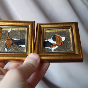 Può includere: Due piccoli dipinti incorniciati di un bassotto nero e bianco. Un dipinto mostra il cane di profilo, l'altro lo mostra di spalle.