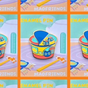 Könnte beinhalten: Emaille-Anstecknadel mit einem farbenfrohen Ramen-Schüssel-Design mit Katzen- und Fischillustrationen. Die Anstecknadel hat einen blauen Deckel, eine gelbe Schüssel und rote Akzente. Der Text "MAOFRIENDS" und "ENAMEL PIN" sind sichtbar.