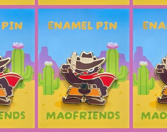 May include: Enamel pin featuring a cartoon bear dressed as a cowboy, holding a gun. The pin has a brown bear with a red cape, cowboy hat, and orange pants. The background is a desert scene with cacti and mountains. The text "ENAMEL PIN" and "MAOFRIENDS" are visible.