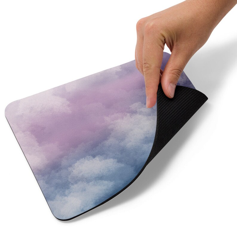 Pu&ograve; includere: Un tappetino per mouse con un design a nuvole acquerellate viola e blu e un retro in gomma nera.