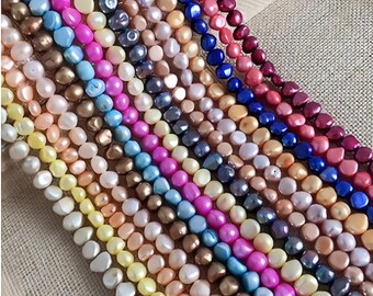 May include: A collection of colorful, irregular-shaped freshwater pearl strands. The pearls vary in shades of pink, blue, yellow, and neutral tones. The strands are arranged diagonally, showcasing the variety of colors and textures.