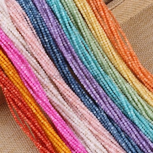 May include: A collection of colorful gemstone beads in various shades, including red, orange, yellow, green, blue, purple, and pink. The beads are strung together, creating a vibrant display of colors. The text "AndySilkpearl4U" is visible.