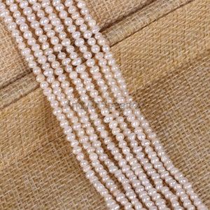 Könnte beinhalten: Mehrere Stränge cremeweißer Perlen, jede mit einer einzigartigen Form, werden vor einem strukturierten, beigefarbenen Hintergrund gezeigt. Die Perlen sind aufgefädelt und bilden Linien potenzieller Schmuckkomponenten. Der Text "AndyDIYpearl4U" ist sichtbar.