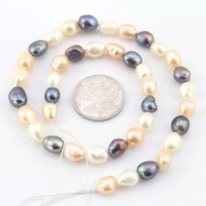 Puede incluir: Un collar de perlas de agua dulce de forma ovalada, en tonos blanco, melocotón y gris oscuro. Las perlas están ensartadas. Una moneda se coloca junto a las perlas para la comparación de tamaño.