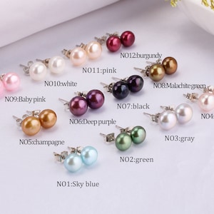 Può includere: Un set di 12 paia di orecchini di perle in vari colori, tra cui bianco, rosa, rosa chiaro, champagne, viola scuro, nero, grigio, verde, azzurro cielo, verde malachite, bordeaux e viola. Ogni paio è etichettato con un numero e un nome di colore.
