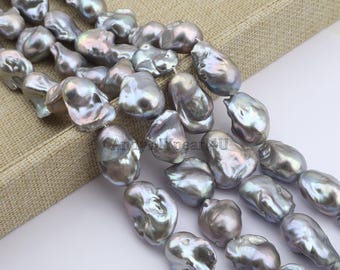 May include: A close-up of strands of large, grey baroque pearls. The pearls have an irregular shape and a shimmering, iridescent surface, reflecting light with silver and purple hues. The pearls are strung together, suitable for jewellery.