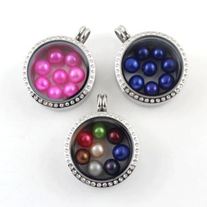 Könnte beinhalten: Drei silberne Anhängerketten mit klaren Glaseinsätzen und Kristallverzierungen. Jeder Anhänger enthält Perlen in verschiedenen Farben: rosa, blau und eine Mischung aus Farben.