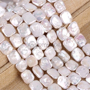 Puede incluir: Primer plano de una colección de perlas blancas de forma irregular. Las perlas tienen un brillo lustroso e iridiscente, que refleja la luz con toques de rosa y azul. Las perlas están dispuestas muy juntas, lo que sugiere que están ensartadas para hacer joyas.