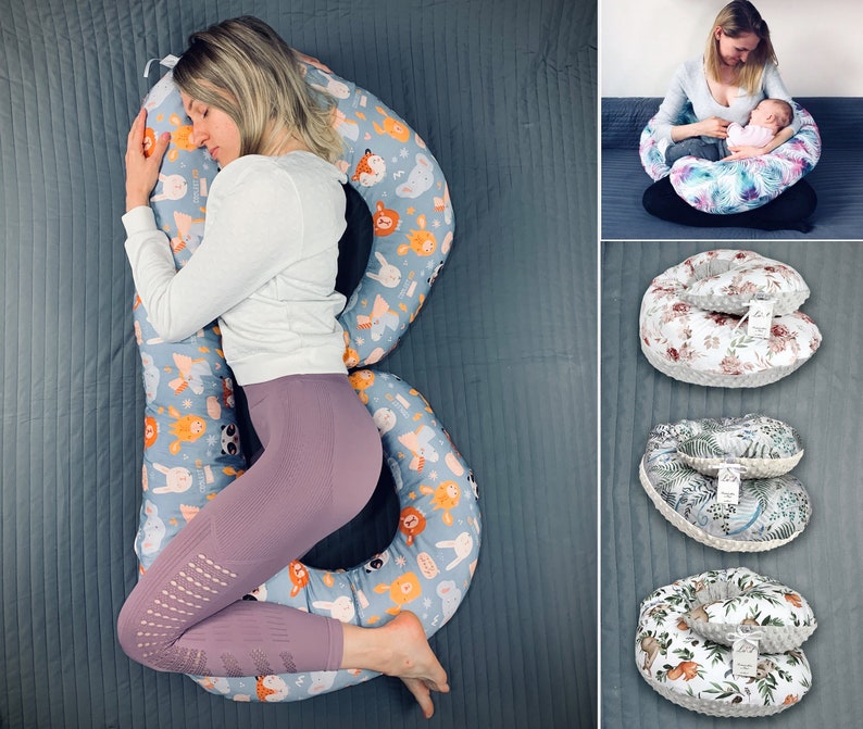 May include: A large, blue and white pregnancy pillow with a colorful animal print design. The pillow is shaped like a letter B and is being used by a person to sleep on their side.