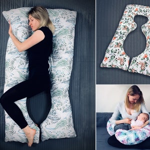 May include: A U-shaped body pillow featuring a white fabric cover with a green and blue fern leaf pattern. The pillow is shown in a full-length configuration for side sleeping and in a smaller, curved configuration for nursing support.
