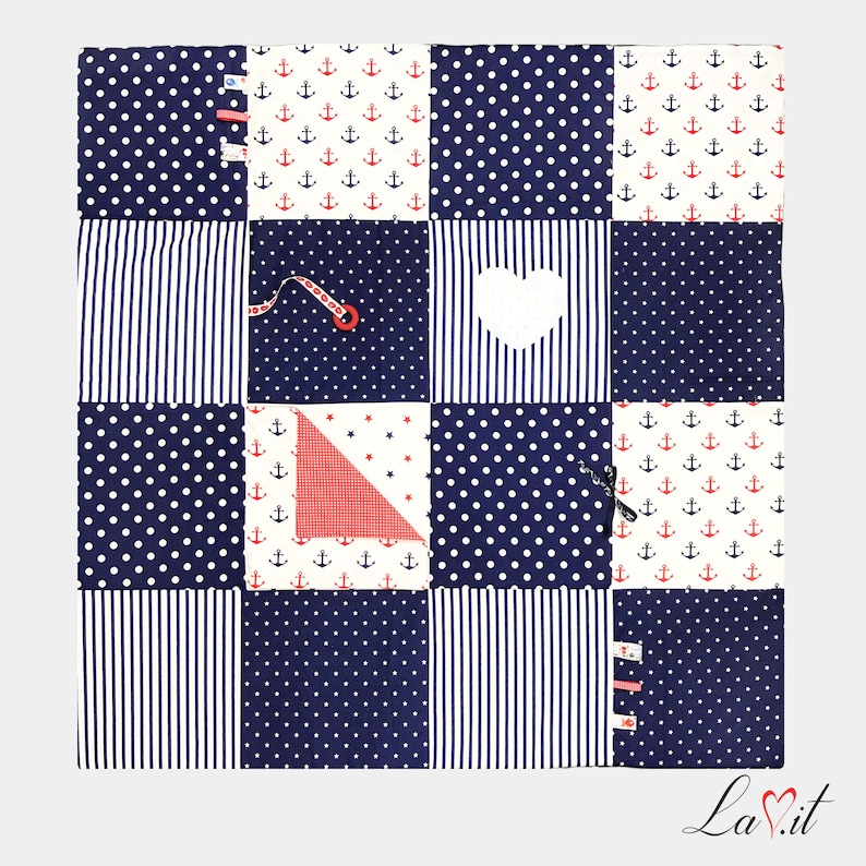May include: A blue and white baby play mat with different textures and patterns. The mat has a heart-shaped cutout, a red triangle, and a zipper. The mat is perfect for babies to explore and learn.