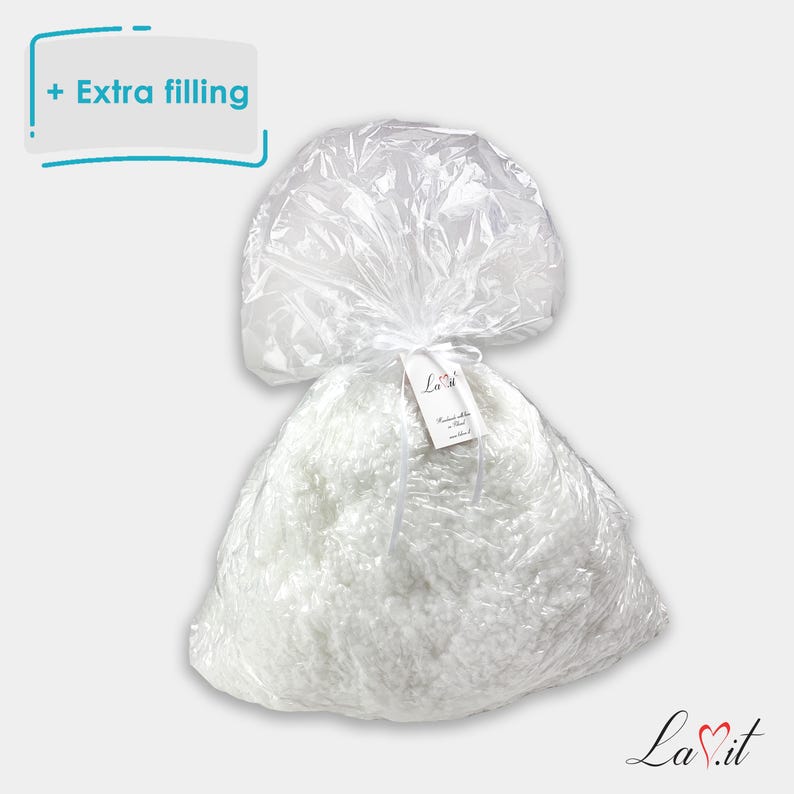Pode incluir: Um saco de pl&aacute;stico transparente cheio de material de enchimento branco e fofo. O saco &eacute; atado no topo com uma fita branca e apresenta uma pequena etiqueta branca com o texto La.it. Um gr&aacute;fico no canto superior esquerdo exibe o texto + Extra filling.