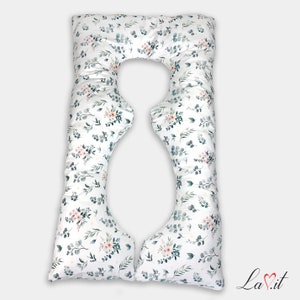 May include: A white U-shaped body pillow featuring a repeating botanical pattern of dark green eucalyptus leaves and small clusters of soft pink flowers. The pillow has a distinct contoured shape with a central cutout and the text La.it in the corner.