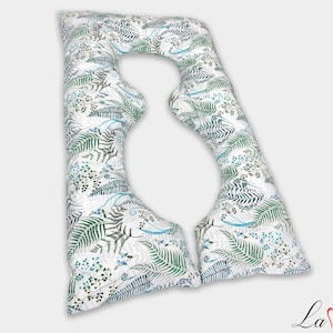 May include: A U-shaped body pillow featuring a white fabric base with a repeating botanical pattern of green fern leaves and small blue sprigs. The pillow has a distinct curved design with two long arms and a rounded top section for support.