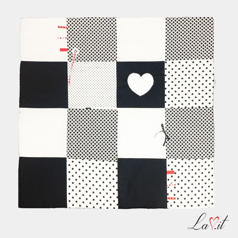 May include: Black and white baby play mat with different patterns, including polka dots, checkered, and a heart shape.
