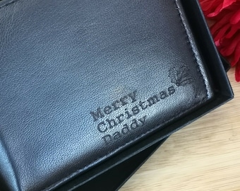 May include: A black leather wallet with the text "Merry Christmas Daddy" and a holly leaf design engraved on the front.