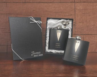 Può includere: Due set regalo di fiaschetta nera incisa con un design da smoking. Le fiaschette sono in scatole nere con un imbuto argentato. Il testo sulle fiaschette recita "Spencer Best Man 15/07/2024" e "Christopher Groomsman 15/07/2024".