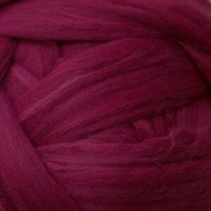 May include: A close-up of a deep magenta colored yarn, showing the texture and softness of the wool fibers.