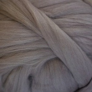 May include: A close-up of a large bundle of soft, light gray yarn. The yarn is thick and fluffy, perfect for knitting or crocheting.