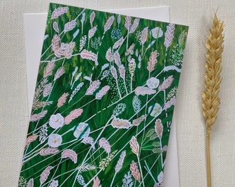 Op de afbeelding: Een groene kaart met een witte envelop. De kaart heeft een handgeschilderde illustratie van een veld met witte en roze bloemen met groene stelen en bladeren.