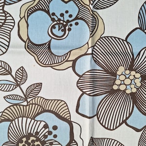 Puede incluir: Una tela blanca con un patrón floral en tonos marrones, azules y beige. Las flores son estilizadas y tienen un diseño geométrico.