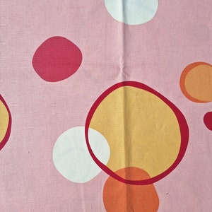 May include: Pink fabric with a repeating pattern of colorful circles. The circles are in shades of red, orange, and white.
