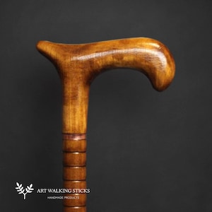 May include: A wooden walking stick with a brown, curved handle and a brown shaft with a copper band. The shaft is also decorated with a series of rings.