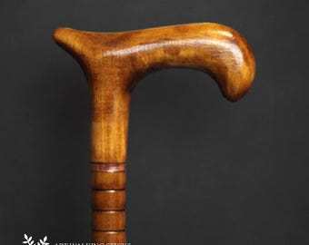 May include: A wooden walking stick with a brown, curved handle and a brown shaft with a copper band. The shaft is also decorated with a series of rings.