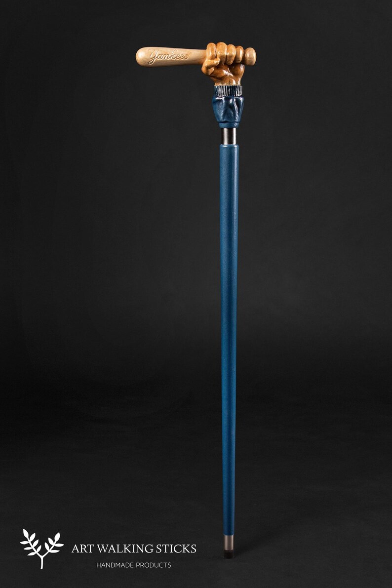 May include: A blue walking stick with a hand holding a wooden baseball bat with the word "Yankees" carved into it.