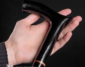 May include: A black walking stick with a curved handle and a copper band. The stick is held in a hand.