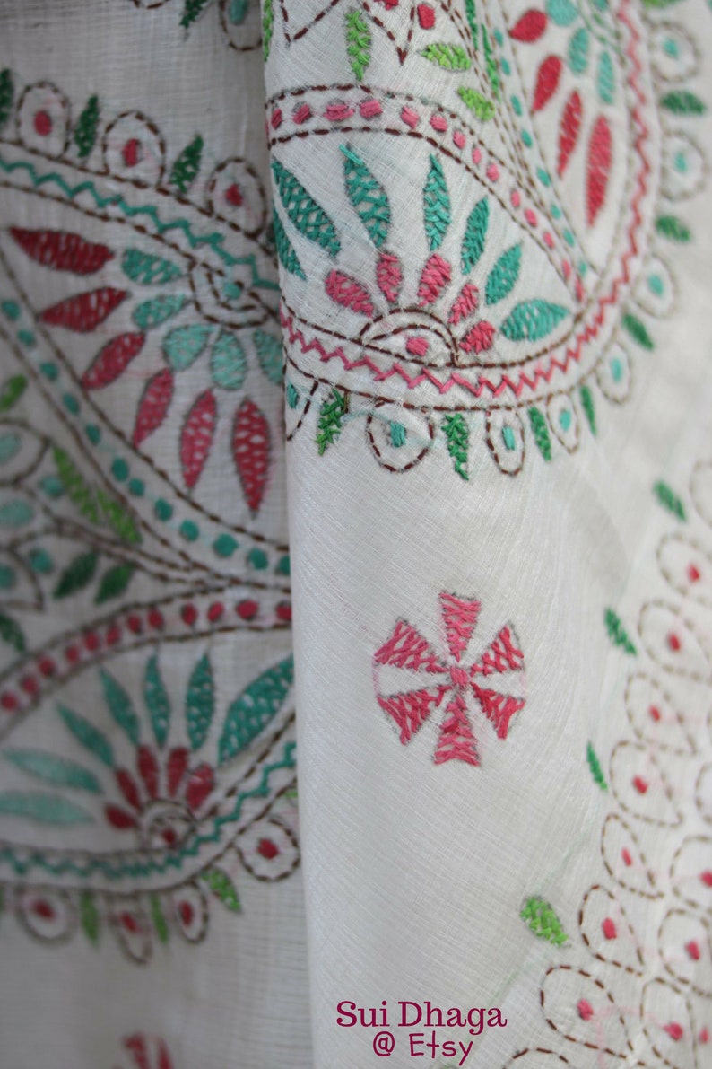 Puede incluir: Primer plano de tela blanca con intrincados bordados en tonos rosa, turquesa y verde. El dise&ntilde;o presenta patrones florales y geom&eacute;tricos, con pespuntes marrones que delinean los detalles. El nombre de la tienda Etsy es visible.