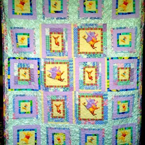 Può includere: Una trapunta con un design a patchwork che presenta più quadrati con uno sfondo blu chiaro e un bordo viola chiaro. Ogni quadrato contiene un'immagine diversa di Winnie the Pooh e i suoi amici. La trapunta è realizzata con una varietà di tessuti e colori, tra cui giallo, verde, rosso e rosa.