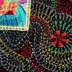 May include: Close-up of a colorful embroidered fabric with a black background. The fabric is decorated with a variety of stitches in different colors, including red, yellow, green, blue, and white. The stitches are arranged in a geometric pattern, creating a visually interesting and intricate design.