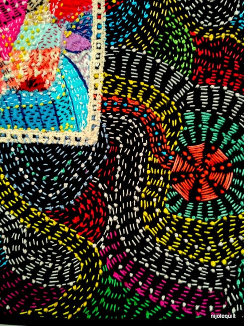 May include: Close-up of a colorful embroidered fabric with a black background. The fabric is decorated with a variety of stitches in different colors, including red, yellow, green, blue, and white. The stitches are arranged in a geometric pattern, creating a visually interesting and intricate design.