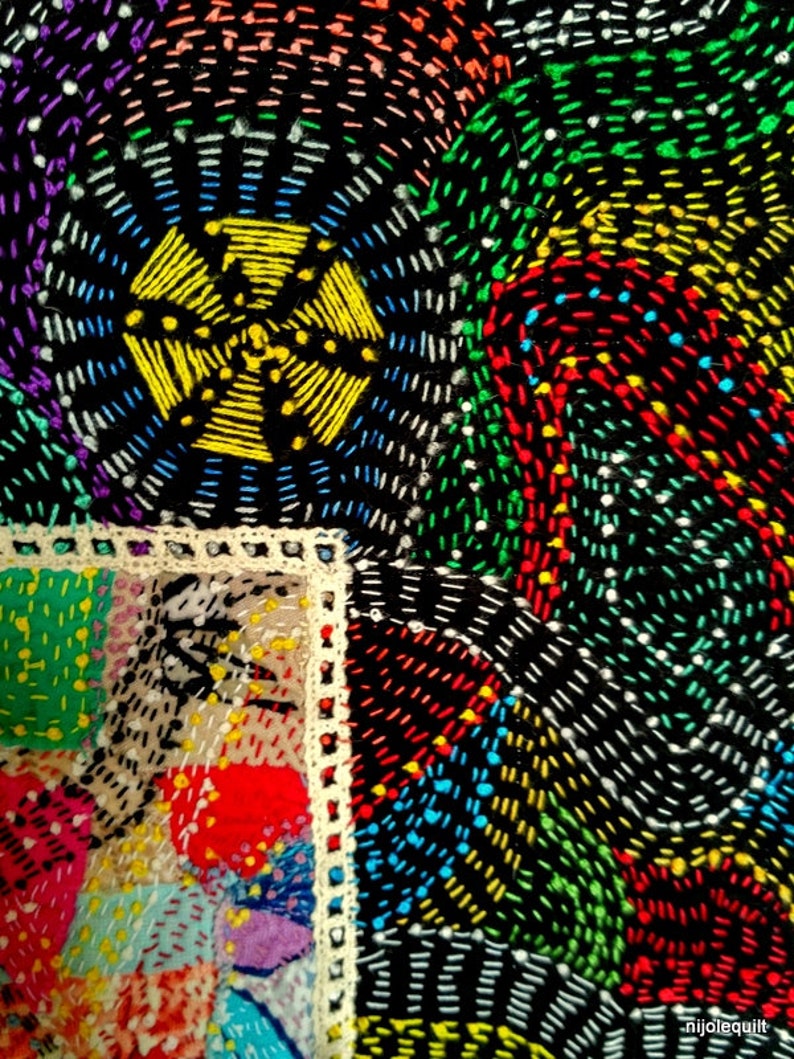 May include: A close-up of a colorful quilt with a variety of stitches and patterns. The quilt is made of different fabrics and colors, including red, green, blue, yellow, and white. The quilt is stitched together with a variety of stitches, including straight stitches, zig-zag stitches, and cross-stitches.