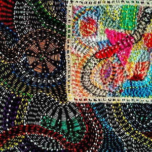 May include: A close-up of a colorful embroidered fabric with a square frame. The fabric is made up of small stitches in various colors, including red, blue, green, yellow, and white. The frame is made of white thread and has a simple design.
