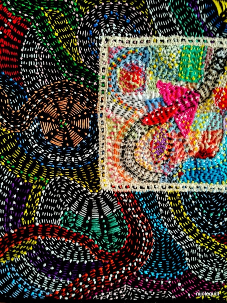 May include: A close-up of a colorful embroidered fabric with a square frame. The fabric is made up of small stitches in various colors, including red, blue, green, yellow, and white. The frame is made of white thread and has a simple design.