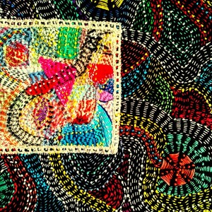 May include: A colorful, intricate embroidery design with a variety of colors, including red, blue, green, yellow, and white. The design is framed by a white border and is set against a black background.