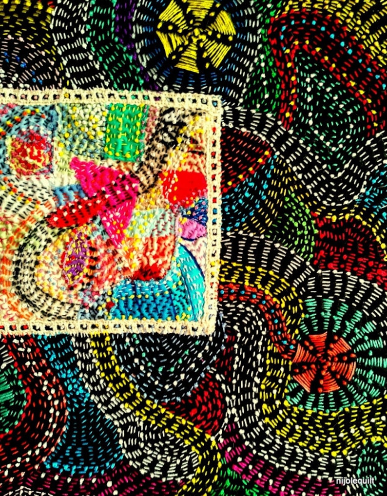 May include: A colorful, intricate embroidery design with a variety of colors, including red, blue, green, yellow, and white. The design is framed by a white border and is set against a black background.