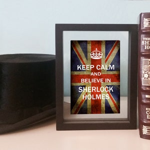May include: A framed print with a vintage Union Jack flag background and the text "Keep Calm and Believe in Sherlock Holmes".
