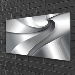 May include: Abstract wall art featuring a swirling, silver design. The design is reminiscent of a metallic wave or a flowing ribbon.